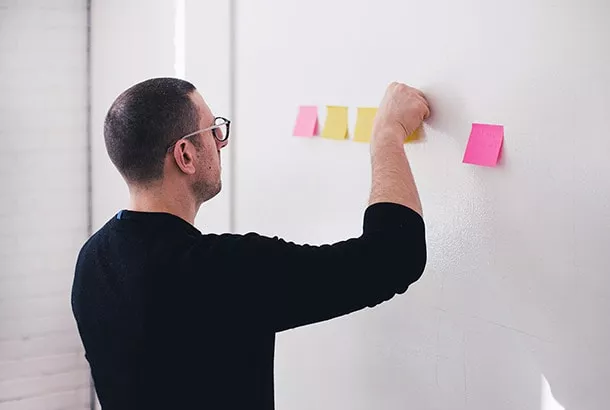 Koordinator planlægger vagter med post-it-sedler på en væg